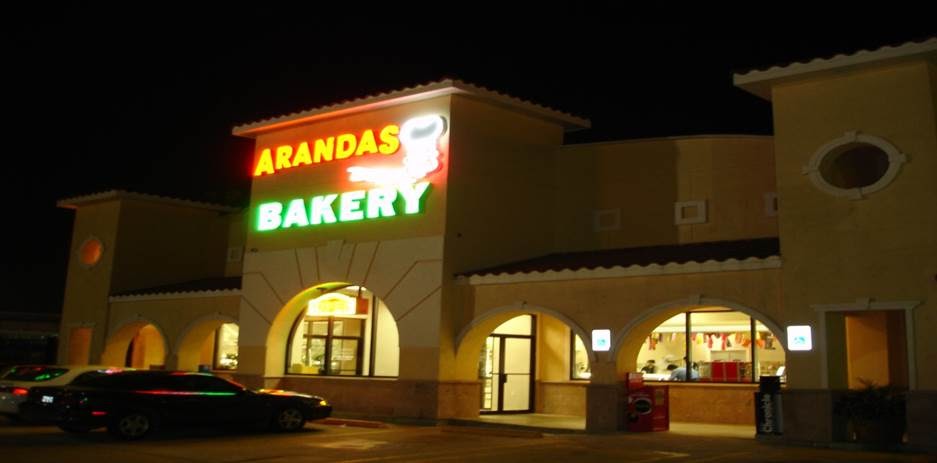 Arandas Bakery storefront at night with illuminated neon sign and stucco building with arched windows at Arandas Bakery