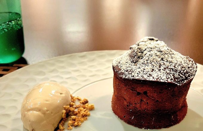Chocolate lava cake with powdered sugar and a scoop of caramel ice cream on a white plate at Barbacana