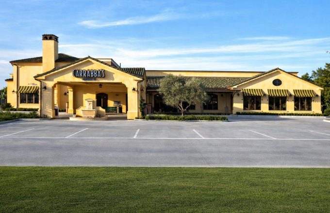 Exterior of Carrabba's on Kirby with Tuscan-style yellow stucco facade clay tile roof striped awnings and fountain entrance in Houston