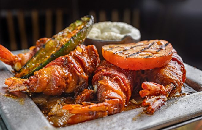 Bacon-wrapped jumbo shrimp with accompaniments on a plate at El Tiempo Cantina — Navigation