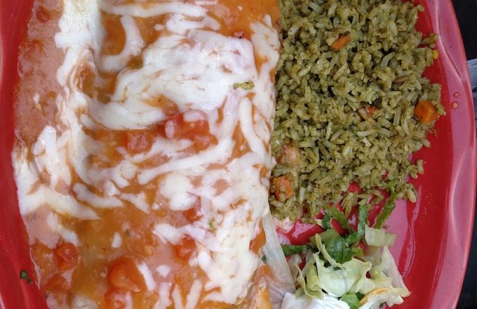 Cheese enchilada plate with green rice, sour cream, and lettuce on a red plate at El Tiempo Cantina