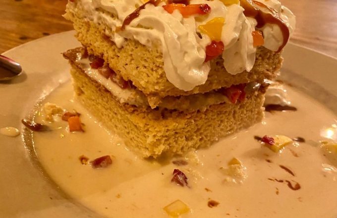 Tres leches cake dessert topped with whipped cream on a plate at El Tiempo Cantina — Navigation