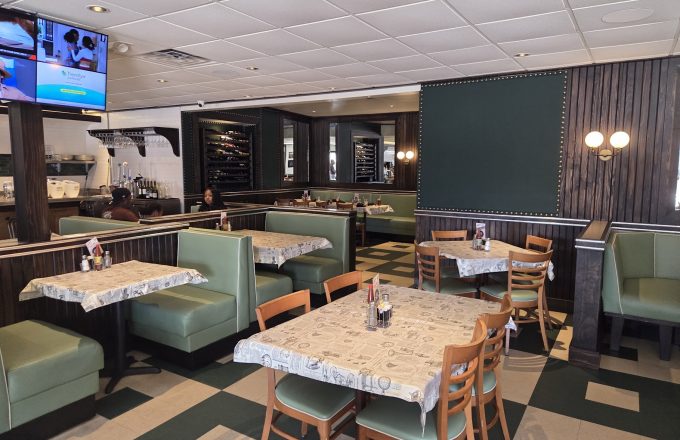 Dining room with green booths wood paneling checkered floor and TVs at Gatlin's Fins and Feathers