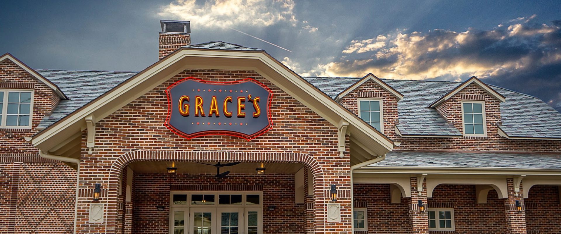 Grace's on Kirby brick restaurant exterior with illuminated sign against dramatic sunset sky on Kirby Drive in Houston