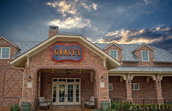 Grace's on Kirby brick restaurant exterior with illuminated sign against dramatic sunset sky on Kirby Drive in Houston