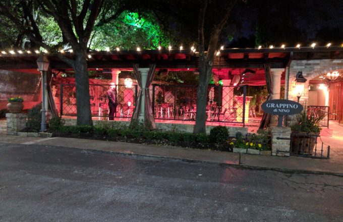 Historical exterior of Grappino di Nino with string lights patio dining and Grappino di Nino sign in the Mandola family Tuscan courtyard on West Dallas Street in Houston