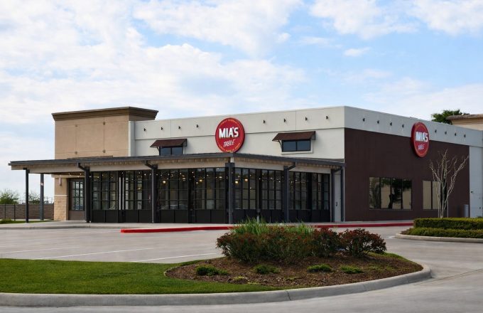 Exterior of Mia's Table Bay Area location in Webster with round Mia's Table sign and large glass windows