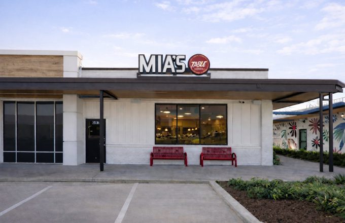 Exterior of Mia's Table Bellaire location with large Mia's Table sign, red benches, and glass entrance