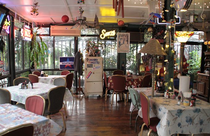 Colorful dining room with floral tablecloths, neon signs, and eclectic vintage decor at Ninfa's on Navigation
