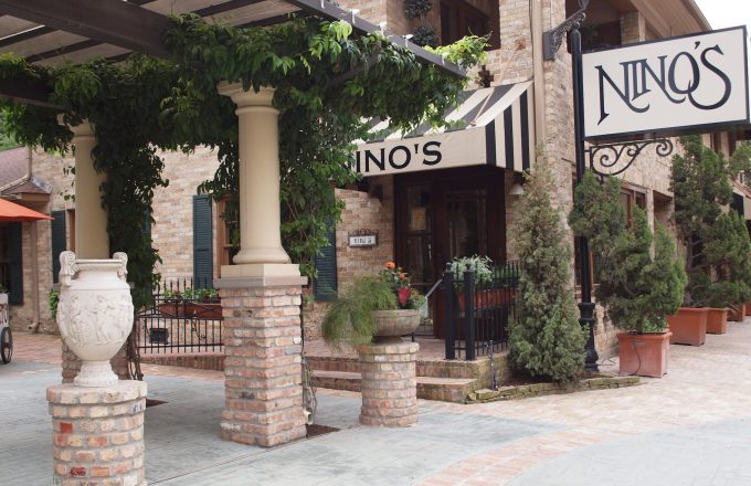 Historical exterior of Nino's Italian restaurant with Nino's sign brick facade striped awning columns and Tuscan courtyard on West Dallas Street in Houston