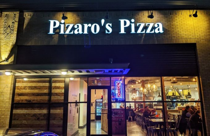 Exterior storefront of Pizaro's Pizza Napoletana with illuminated signage at night in Houston