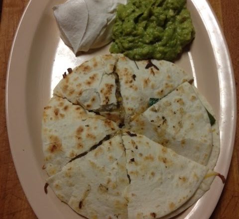 Quesadilla cut into quarters with guacamole and sour cream on a white plate at Rio Grande Tex-Mex Grill