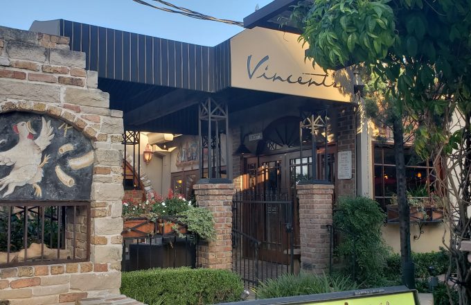 Historical exterior of Vincent's Italian restaurant with Vincent's sign stone facade rooster mural and Tuscan courtyard on West Dallas Street in Houston