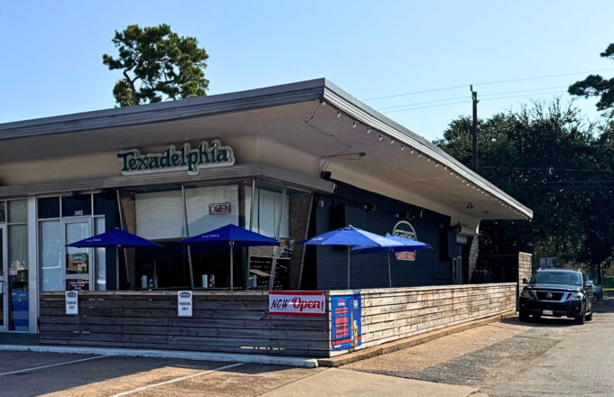 Texadelphia Garden Oaks cheesesteak restaurant exterior with blue patio umbrellas and signage